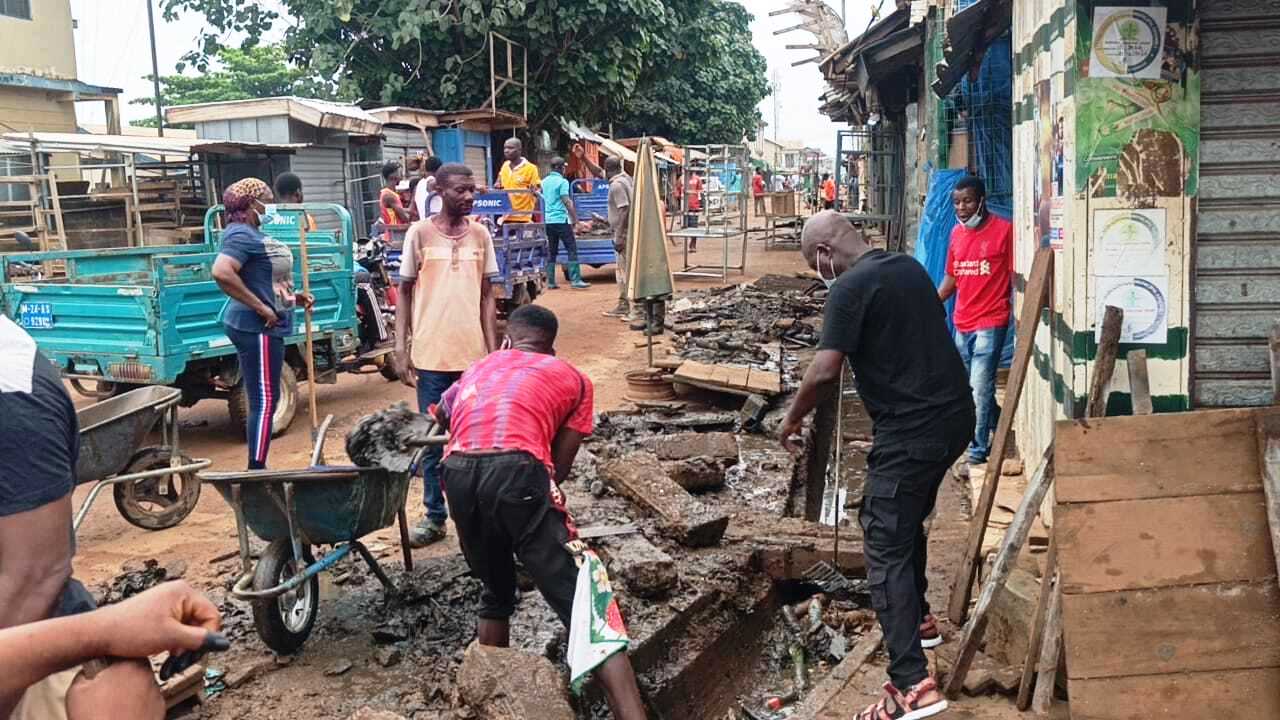 Volunteers scooping plastic waste from drains
